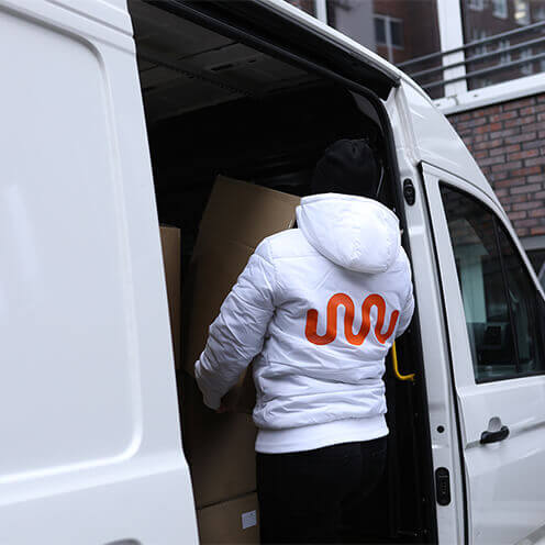 Promoter mit kununu Logo auf der Jacke räumt Lieferwagen aus. 